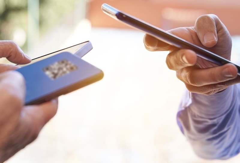 Duas mãos segurando celulares próximos um do outro