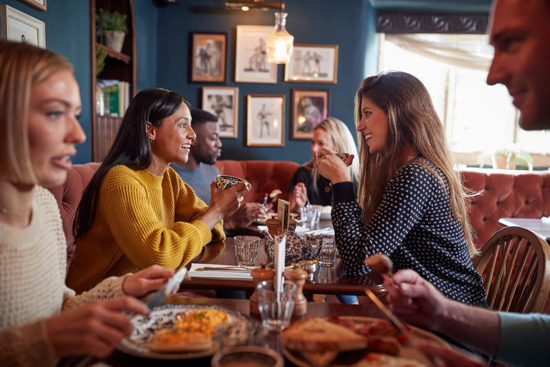 Pessoas conversando e se divertindo em mesas de restaurante