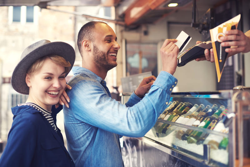 Casal sorrindo com a experiência de compra e realizando pagamento com cartão por aproximação em food truck